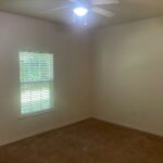 Empty bedroom with window and ceiling fan.