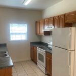 Small apartment kitchen with wood cabinets.