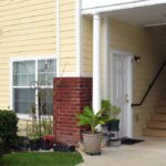 Apartment building entrance with stairs and plants.