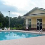 Community pool with building and chairs.